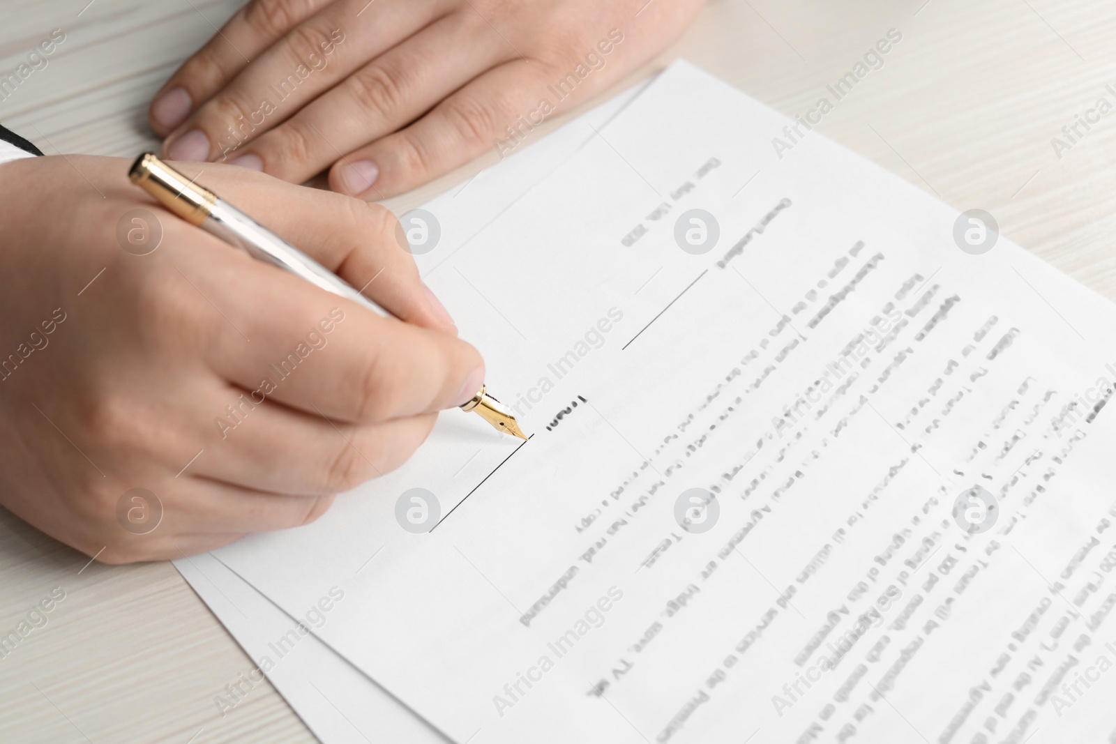 Photo of Notary signing document at wooden table, closeup