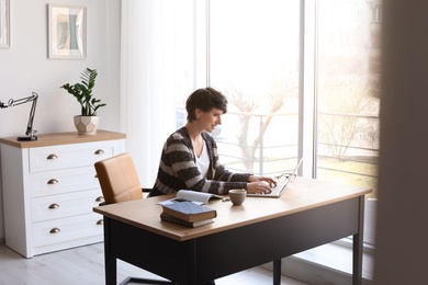 Young woman working with laptop at desk. Home office