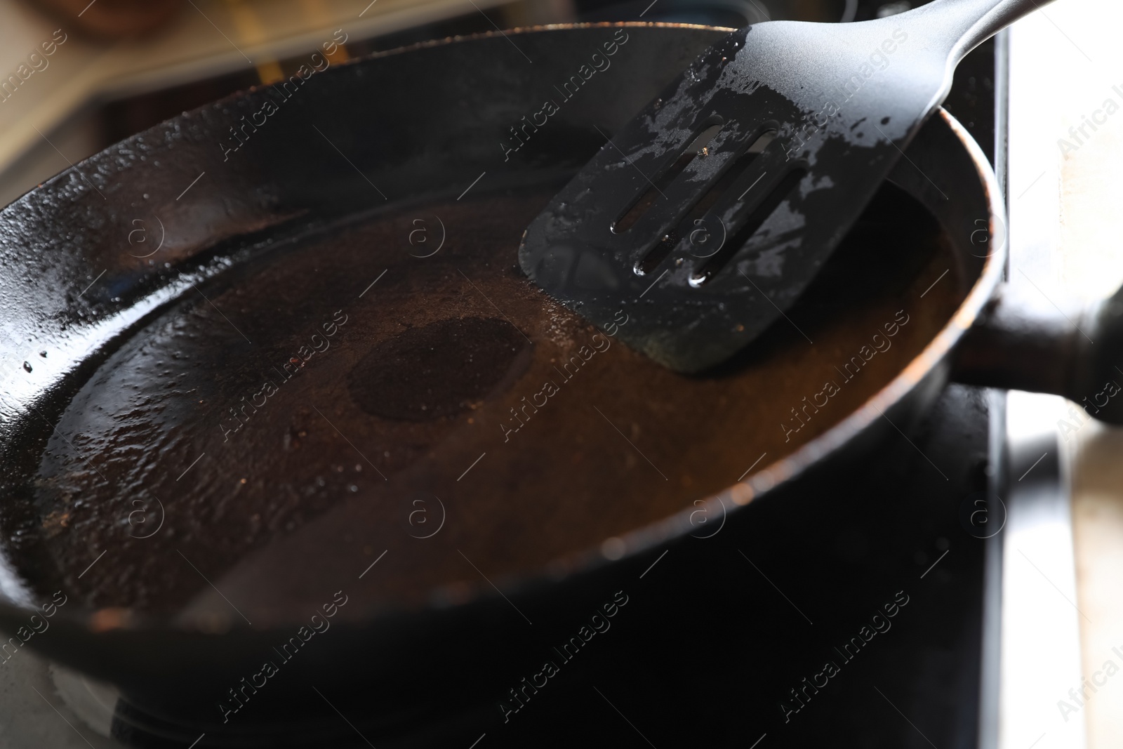 Photo of Frying pan with spatula and used cooking oil on stove, closeup