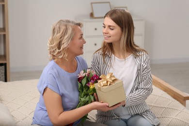 Young daughter congratulating her mom with gift at home. Happy Mother's Day