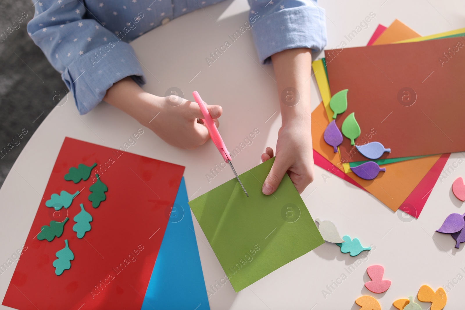 Photo of Little girl making greeting card at table indoors, top view. Creative hobby