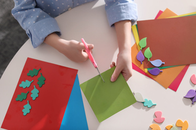 Little girl making greeting card at table indoors, top view. Creative hobby