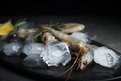 Raw shrimps with ice on grey table, closeup