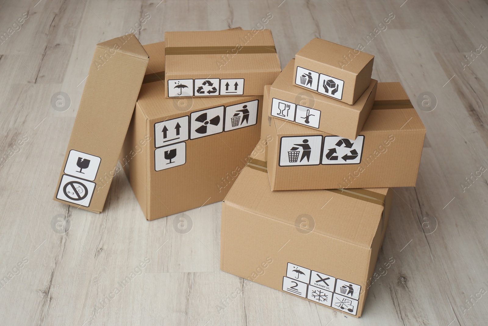 Photo of Cardboard boxes with different packaging symbols on floor. Parcel delivery