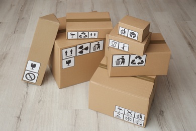 Cardboard boxes with different packaging symbols on floor. Parcel delivery
