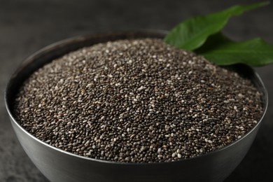 Photo of Metal bowl with chia seeds on grey table, closeup