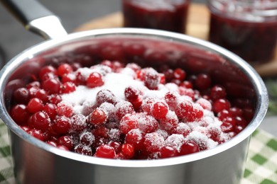 Photo of Making cranberry sauce. Fresh cranberries with sugar in saucepan on table, closeup