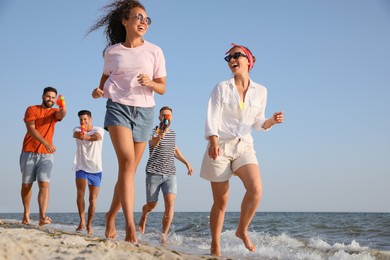 Photo of Group of friends with water guns having fun on beach