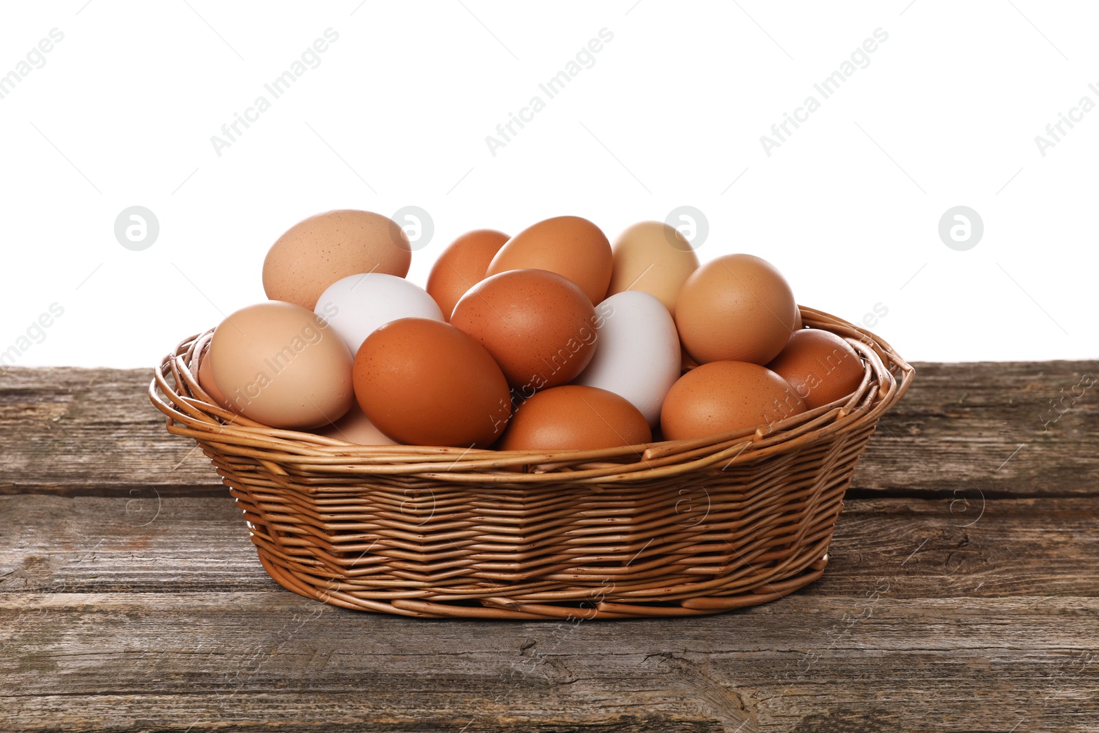 Photo of Fresh chicken eggs in wicker basket on wooden table against white background
