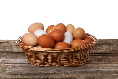 Fresh chicken eggs in wicker basket on wooden table against white background