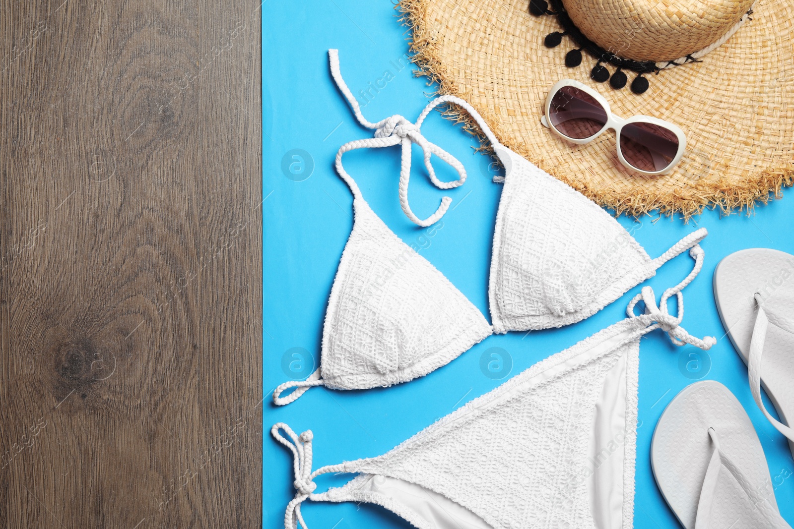 Photo of Flat lay composition with stylish beach accessories on blue paper and wooden background, space for text