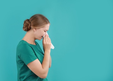 Photo of Young woman suffering from allergy on turquoise background. Space for text