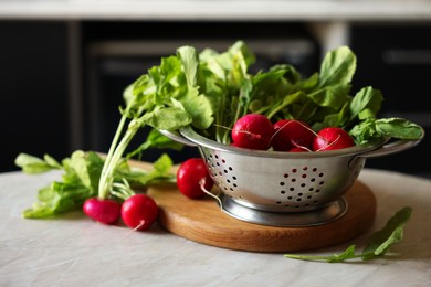 Photo of Metal colander with fresh radishes on white table