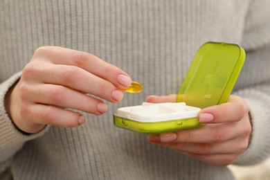 Woman taking pill from plastic box, closeup of hands