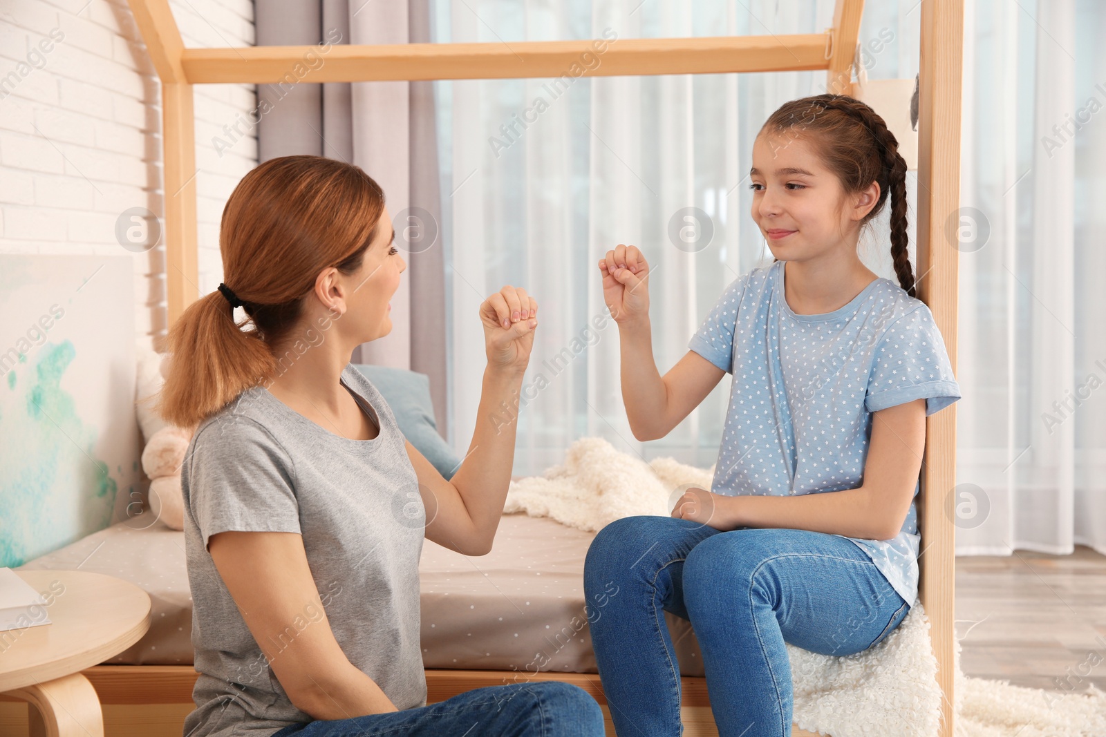 Photo of Hearing impaired mother and her child talking with help of sign language indoors