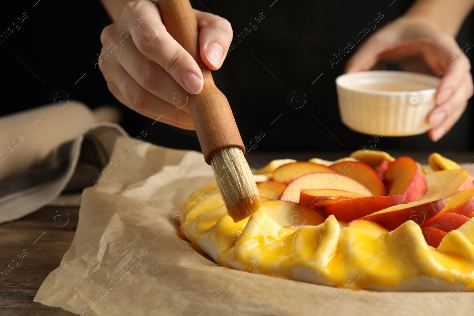 Photo of Woman making peach pie at table, closeup