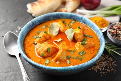 Photo of Bowl of delicious chicken curry on black table