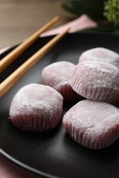 Delicious mochi and chopsticks on black plate, closeup. Traditional Japanese dessert