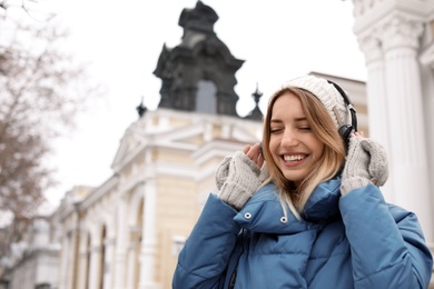 Young woman with headphones listening to music outdoors. Space for text