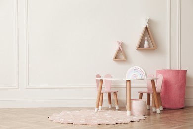 Cute child room interior with furniture, toys and wigwam shaped shelves on white wall. Space for text