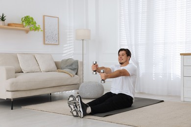 Photo of Overweight man doing exercise with dumbbells on mat at home