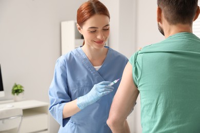 Doctor giving hepatitis vaccine to patient in clinic