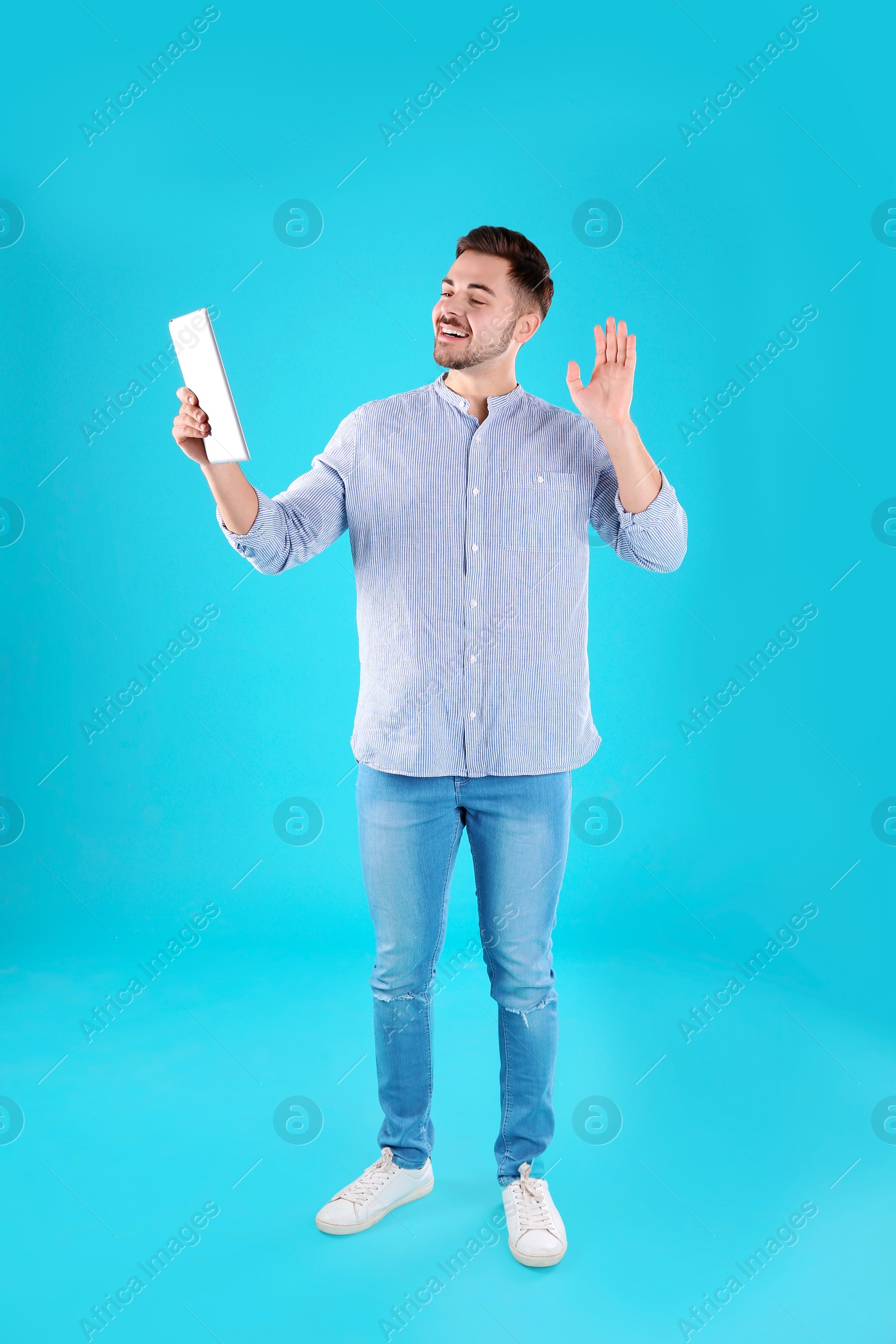 Photo of Man using tablet for video chat on color background