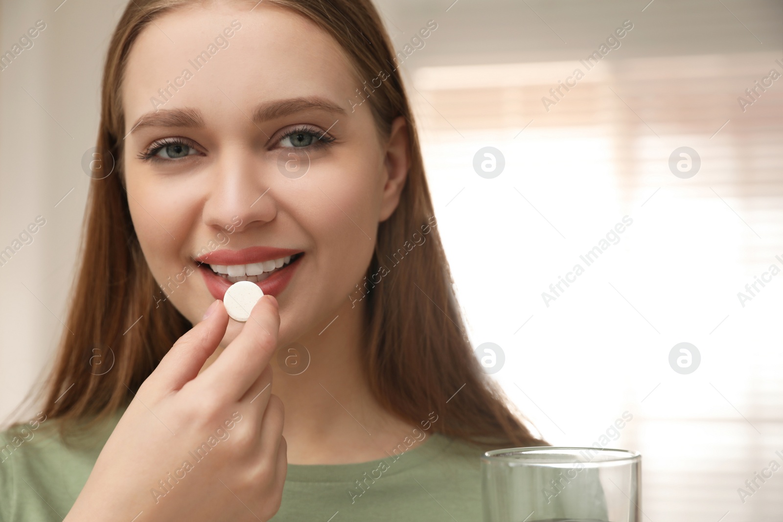 Photo of Young woman taking vitamin pill at home
