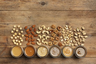 Photo of Nut butters in bowls and ingredients on wooden table, flat lay