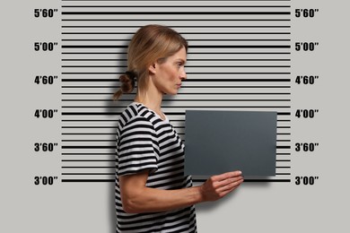 Criminal mugshot. Arrested woman with blank card against height chart