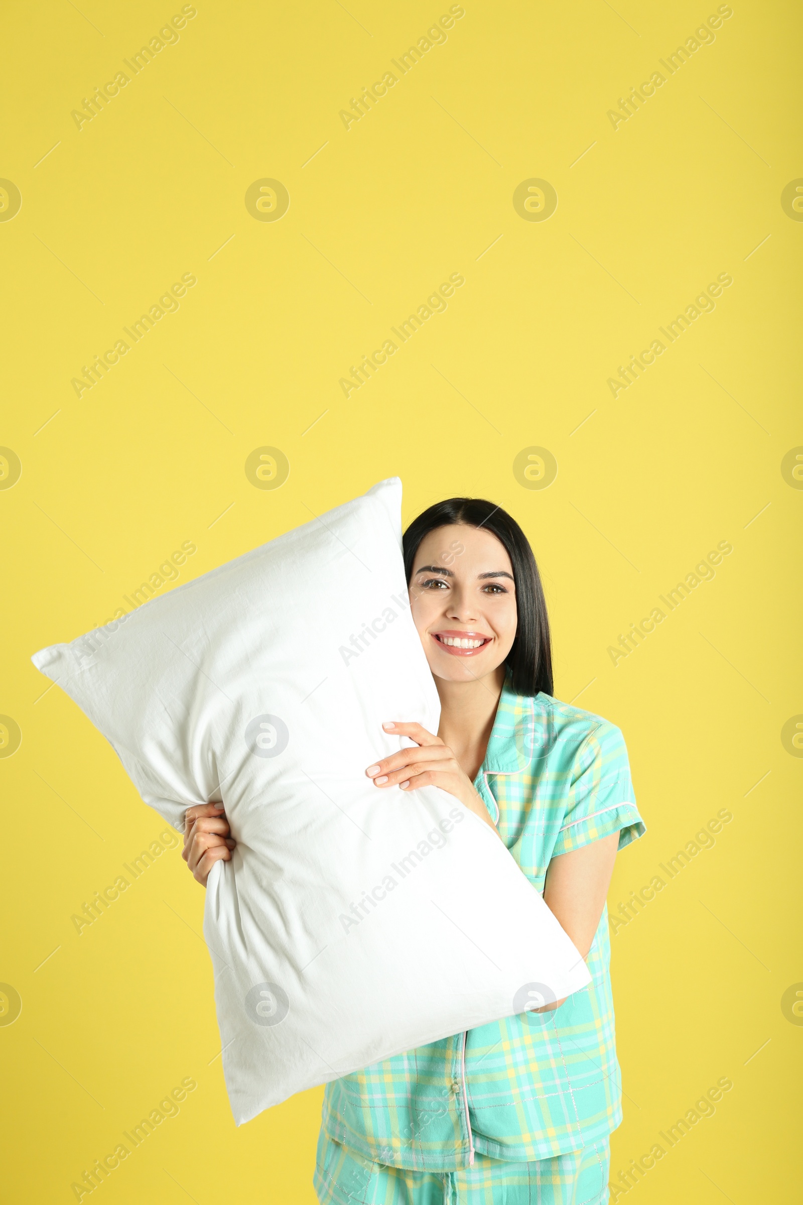 Photo of Young woman with pillow on yellow background