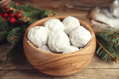 Tasty snowball cookies in bowl and Christmas decorations on wooden table