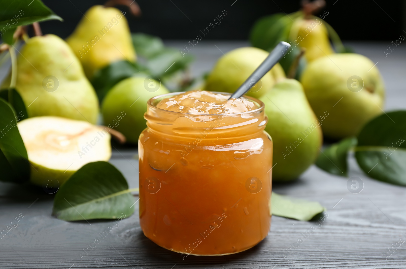 Photo of Delicious pear jam and fresh fruits on grey wooden table