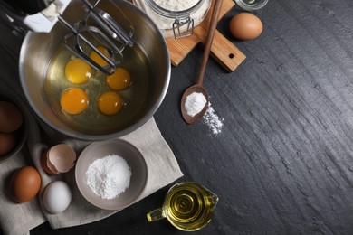 Making dough. Raw eggs in bowl of stand mixer and ingredients on black table, flat lay with space for text