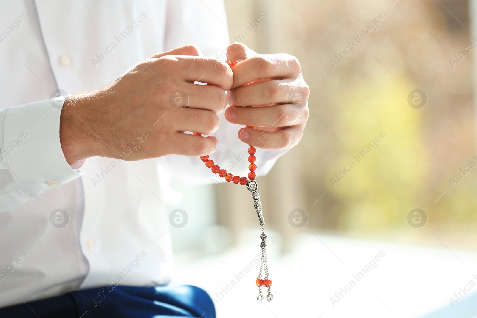 Photo of Muslim man with misbaha praying indoors, closeup