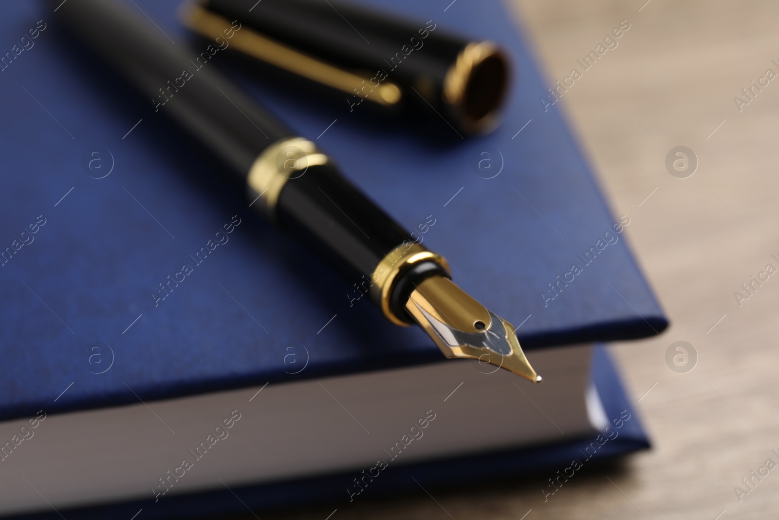 Photo of Beautiful fountain pen and blue notebook on table, closeup