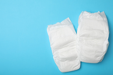 Photo of Baby diapers on light blue background, flat lay. Space for text