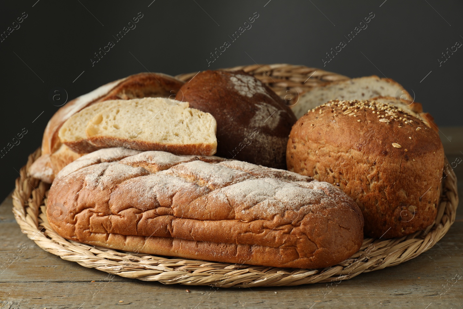 Photo of Wicker basket with different types of fresh bread on wooden table