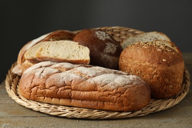 Wicker basket with different types of fresh bread on wooden table