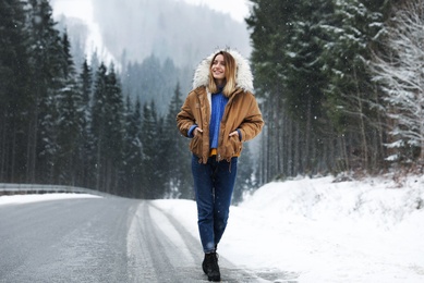 Young woman walking near snowy forest. Winter vacation