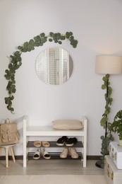 Hallway interior with stylish furniture and round mirror on light wall