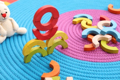 Photo of Colorful wooden pieces of playing set on color mat. Educational toy for motor skills development