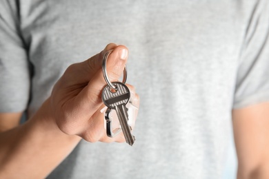 Photo of Young man holding house key with trinket, closeup