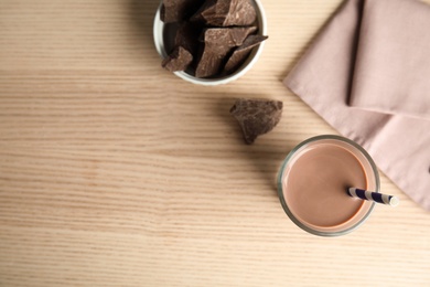Photo of Flat lay composition with glass of tasty chocolate milk and space for text on wooden background. Dairy drink
