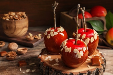 Photo of Delicious caramel apples on wooden serving board