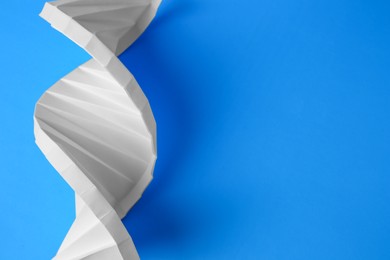 Photo of Paper model of DNA molecular chain on light blue background, above view. Space for text