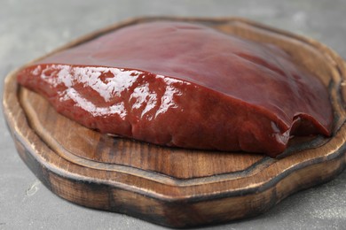 Photo of Piece of raw beef liver on grey table, closeup