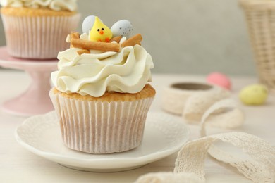 Photo of Tasty Easter cupcake with vanilla cream on light wooden table