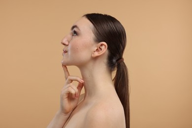Beautiful woman touching her chin on beige background