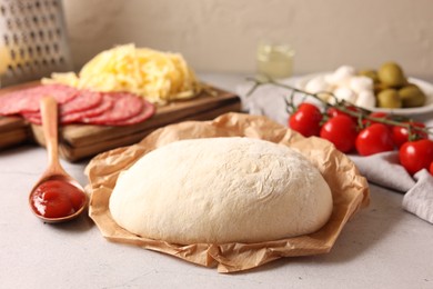 Photo of Pizza dough and products on gray textured table, closeup